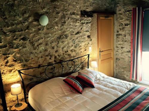 - un lit avec deux oreillers dans une chambre dotée d'un mur en pierre dans l'établissement Le Cabanon d'Entrevon, à Malaucène