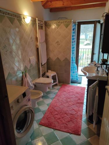 a bathroom with a toilet a sink and a washing machine at Casa Andrea in Cadarese