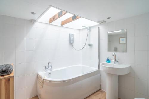 a bathroom with a tub and a sink and a shower at Gatesgarth Cottage @ The Pheasant Inn in Brampton