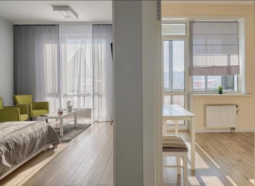 1 dormitorio con cama, mesa y ventanas en Raisson Ahotel D86, en Astana