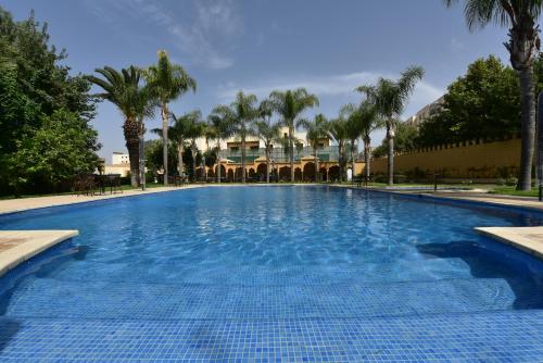 a large swimming pool with palm trees in the background at Hôtel Fès Inn & SPA in Fès