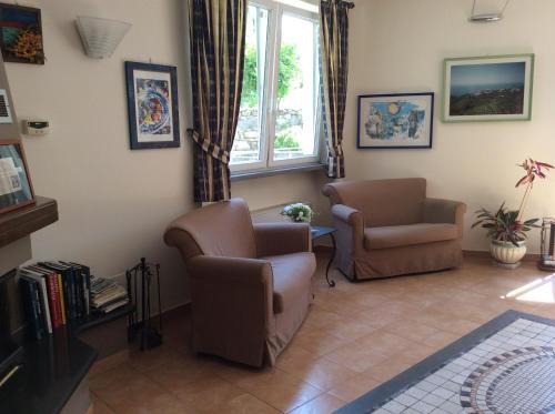 a living room with two chairs and a window at Hotel Il Saraceno in Volastra