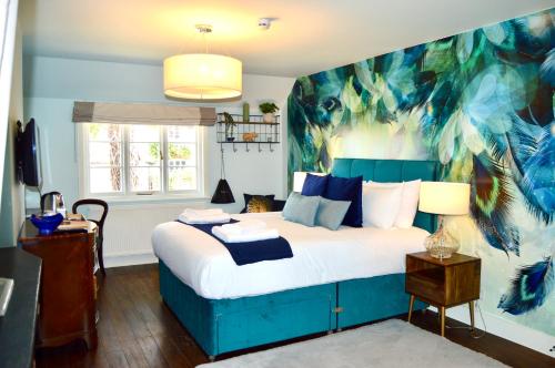 a bedroom with a blue bed with a painting on the wall at The Nest Hotel & Restaurant in Petersfield
