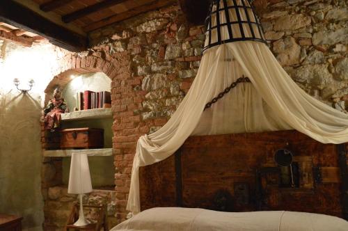 1 dormitorio con cama con dosel en una pared de piedra en Casa Antica, en Castiglione dʼOrcia