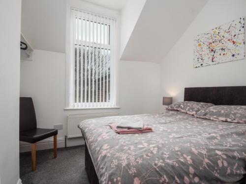 een slaapkamer met een bed, een stoel en een raam bij Apex Living NE - Beachville House 4 Beds FREE PARKING in Sunderland