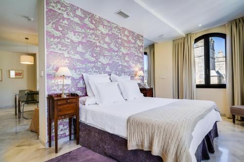 ein Schlafzimmer mit einem großen Bett mit einer lila Wand in der Unterkunft Suites Murillo Alcázar in Sevilla