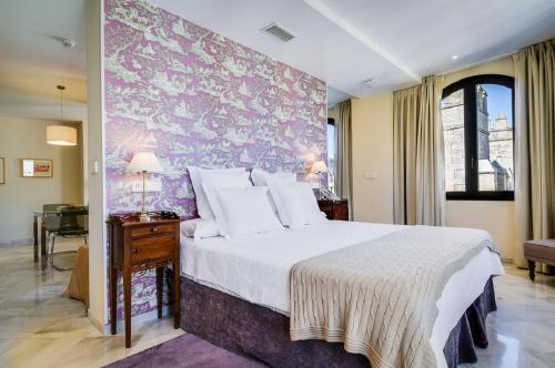 a bedroom with a large bed with a purple wall at Suites Murillo Alcázar in Seville