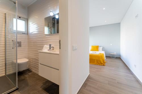 Un baño con lavabo, inodoro y una cama. en Apartamento T2 Kress Property, en Pederneira