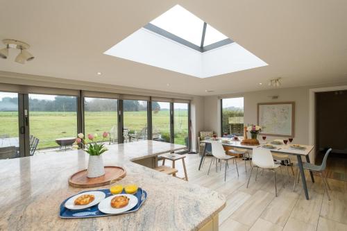 a kitchen and dining room with a large skylight at White Cottage, Iken - Aldeburgh Coastal Cottages in Snape
