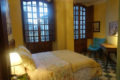 Schlafzimmer mit einem Bett, einem Schreibtisch und Fenstern in der Unterkunft Vivienda Turistica Santa Maria de la Sierra in Cazorla