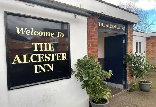 um sinal para a estalagem alchester ao lado de um edifício em Alcester Inn em Alcester