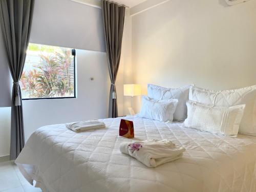 een slaapkamer met een wit bed met een doos erop bij Blanc Residence in Pipa
