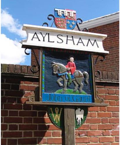 a sign on a building with a person riding a horse at Maple Hut Four Acre Farm in Aylsham