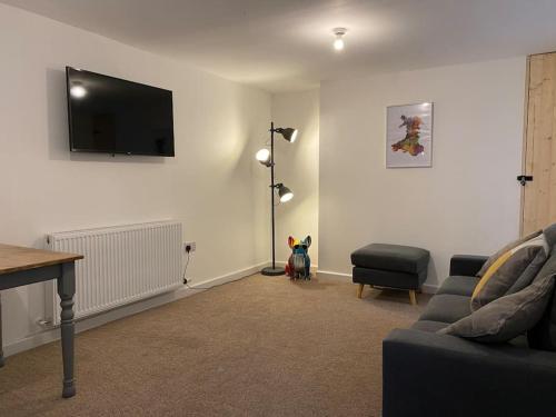 a living room with a couch and a tv on the wall at Modern 2 bedroom cottage near Bike Park Wales. in Merthyr Tydfil