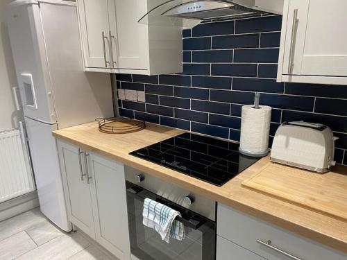 a kitchen with a counter and blue tiles on the wall at Modern 2 bedroom cottage near Bike Park Wales. in Merthyr Tydfil