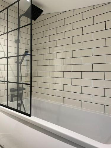 a bathroom with a window and a white brick wall at Modern 2 bedroom cottage near Bike Park Wales. in Merthyr Tydfil