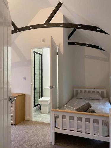 a bedroom with a bed and a bathroom with a mirror at Modern 2 bedroom cottage near Bike Park Wales. in Merthyr Tydfil
