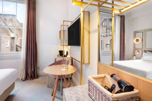 a hotel room with a bed and a desk and a table at Meliá London Kensington Member of Meliá Collection in London