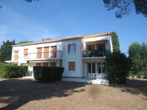 une grande maison blanche avec des arbres devant dans l'établissement Les Lucioles, à Cavalaire-sur-Mer