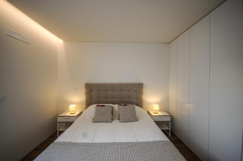 a bedroom with a bed and two lights on two tables at Aljube Residences III - Apart novo no centro de PDL in Ponta Delgada