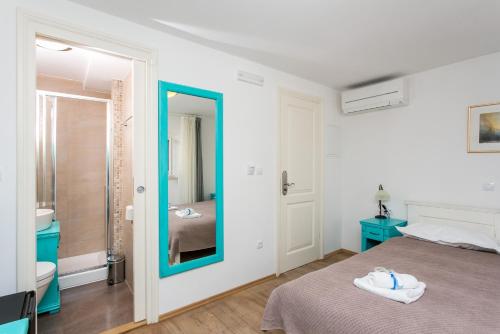 a bedroom with a bed and a bathroom with a mirror at Lumin Guest House in Dubrovnik