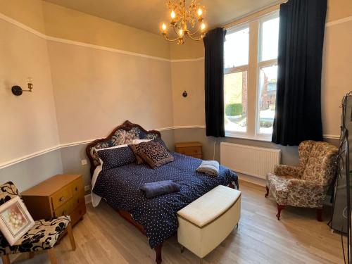 a bedroom with a bed and a chair and a window at Red Gables - Ground Floor in Carlisle