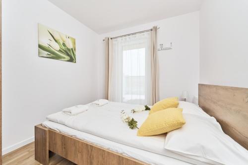 a bed with white sheets and yellow pillows in a room at Apartment Krakowska 39 with AC & PARKING & LOGGIA Wrocław by Renters in Wrocław