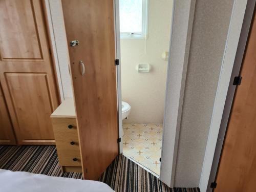 a small bathroom with a toilet and a door at 6 Berth Kingfisher (Firs) in Ingoldmells