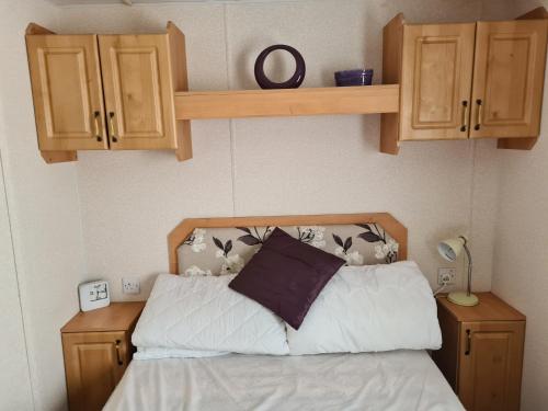 a bedroom with a bed and some wooden cabinets at 6 Berth Kingfisher (Firs) in Ingoldmells