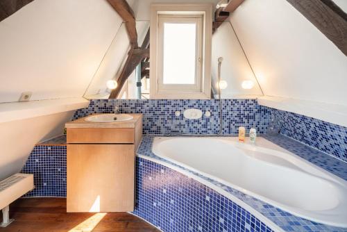 a blue tiled bathroom with a tub and a window at The Hendrik House in Old Town Antwerp in Antwerp
