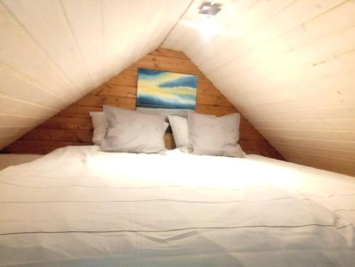 a bed with white sheets and pillows in a attic at 25qm großes Ferienhäuschen " Der Hengstall" auf unserem Reiterhof in Birkenbeul
