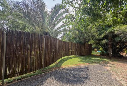 a wooden fence in front of a yard with trees at Suikerbosrant Sleep and go in Pretoria