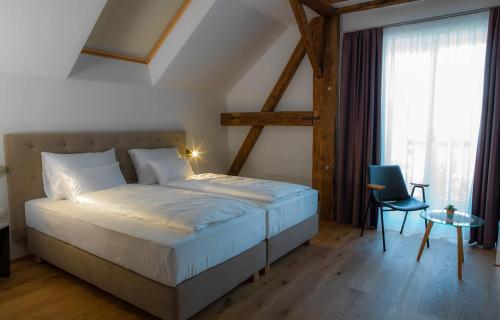 a bedroom with a bed and a chair and a window at Hotel Belmur in Murska Sobota