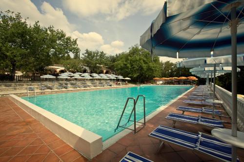 a swimming pool with blue chairs and umbrellas at Luxor Chianti Glamping village in Castellina in Chianti