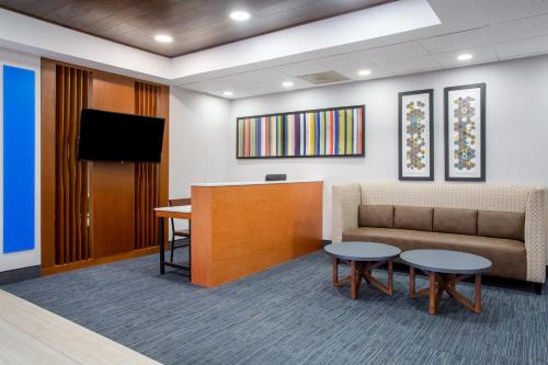 a waiting room with a couch and a tv at Holiday Inn Express Hotel & Suites Fort Wayne by IHG in Fort Wayne