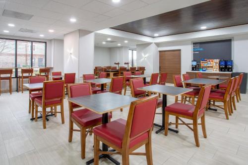 a dining room with tables and red chairs at Holiday Inn Express Hotel & Suites Fort Wayne by IHG in Fort Wayne