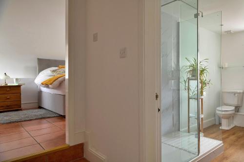 a glass shower in a bedroom with a bed at Finest Retreats - Moelis Granary - Luxury Cottage with Hot Tub in Llandrillo