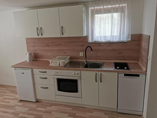 una cocina con armarios blancos y fregadero en Apartments Henigman, en Bohinj