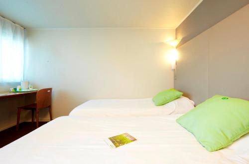 two beds in a hotel room with a book on them at Campanile Biarritz in Biarritz