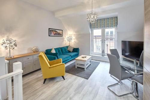 a living room with a blue couch and a tv at Host & Stay - Mallard Cottage in Whitby