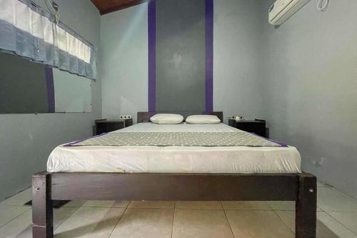 ギリ・トラワンガンにあるMbah Mek Trawangan Homestayの紫の壁の客室の大型ベッド1台