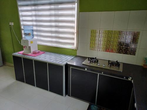 a kitchen with a counter and a sink and a window at Homestay Dalia, Beseri, Perlis in Kangar