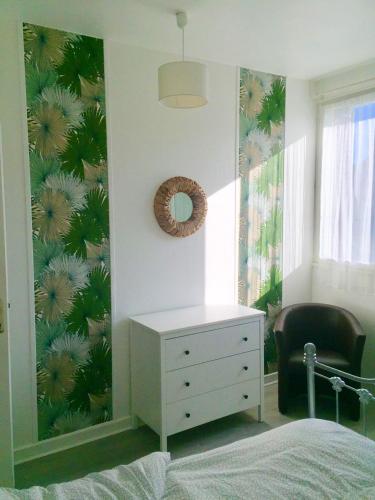 een slaapkamer met een wit dressoir en een muur met tropisch behang bij Appartement d'une chambre avec wifi a Rosny sous Bois in Rosny-sous-Bois