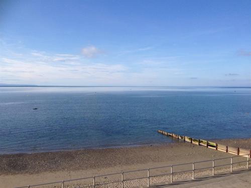 a beach with a fence next to the water at Glanllifon B&B in Criccieth