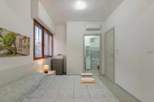 a white bedroom with a bed and a door at Bellariva Home in Florence
