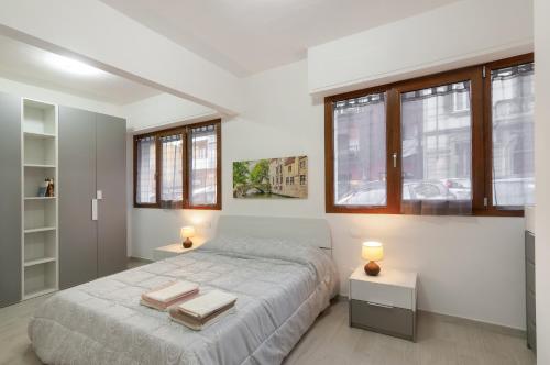 a bedroom with a bed and two tables and windows at Bellariva Home in Florence