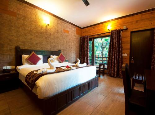 una camera da letto con un grande letto con cigni di Rega Tuskar's Riverside Resort Jim Corbett a Ramnagar