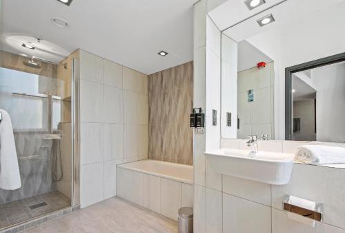 a white bathroom with a sink and a shower at Roomzzz Manchester Victoria in Manchester