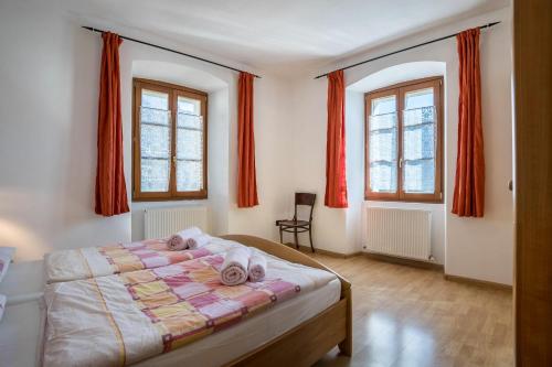 sypialnia z łóżkiem i 2 oknami z czerwonymi zasłonami w obiekcie Residence Lena App 4 w mieście Tenno