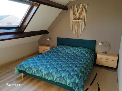 a bedroom with a blue bed and a window at Le Cerisier in Bioul